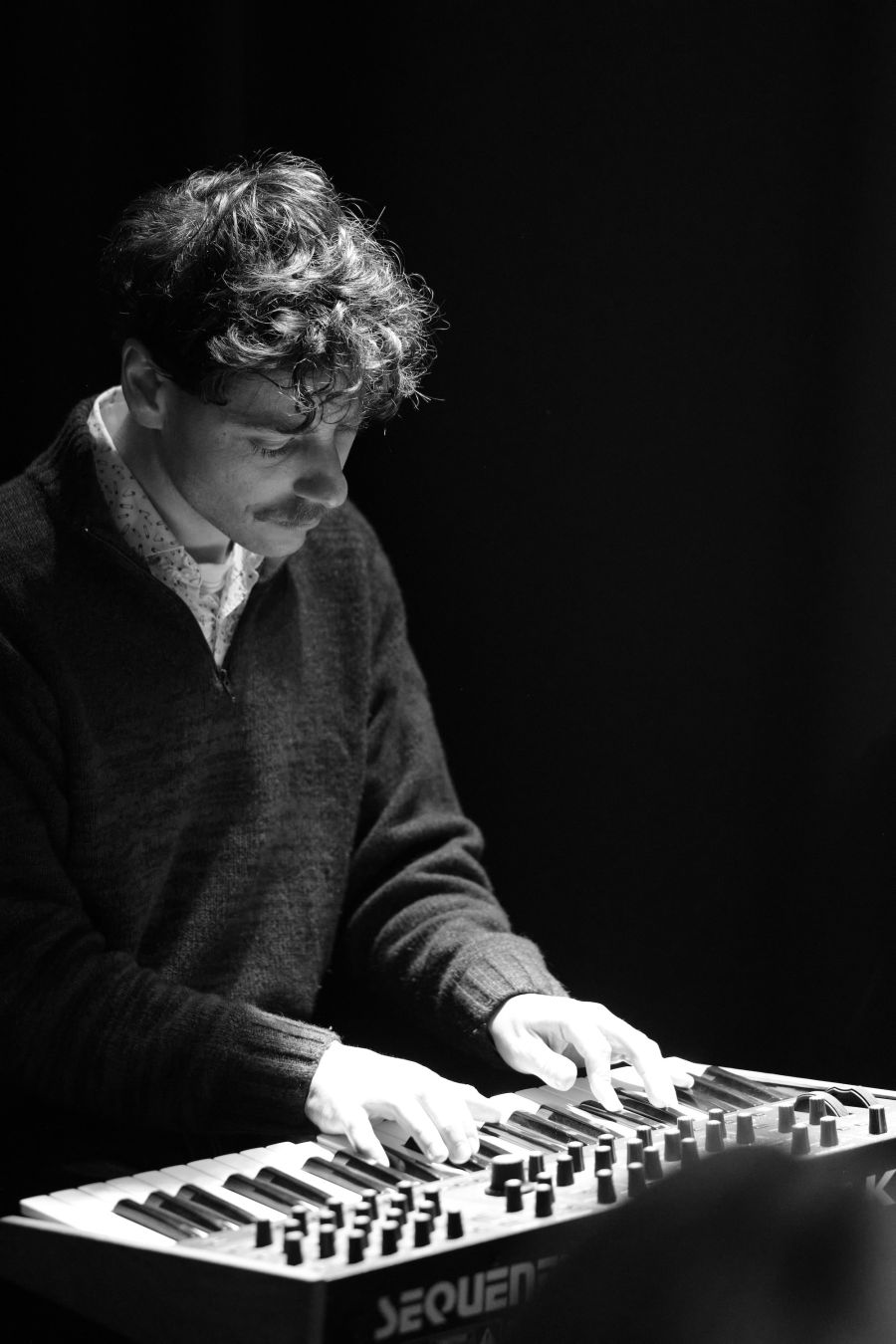 Young woman laughing behind the microphone. Light on her hair and shoulders. She is looking upwards. Black background, picture in black and white.